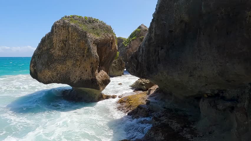 Striking seascape of large rock formations with waves crashing against them under a clear blue sky at Aguadilla coast, Puerto Rico.