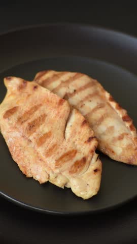 Delicious fresh grilled chicken fillet with spices and herbs on a dark concrete background. A dish cooked over fire