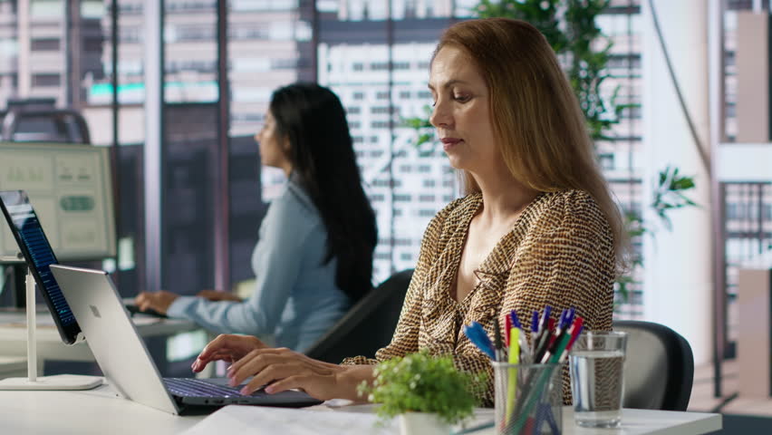 Professional manager at a multinational company works on laptop to track project progress and deadline completion. Office worker ensuring smooth task management and decision making. Camera A.