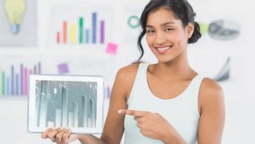 Pointing at tablet with financial data animation, woman smiling in office. Business, technology, finance, professional, working, analysis - Powered by Shutterstock - Get 15% off with code: PIKWIZARD15