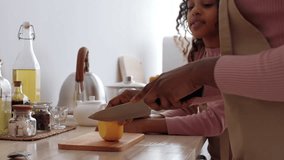 In a cozy kitchen, black woman gently guides a child as they slice an orange together. The warm atmosphere encourages learning and bonding during this shared cooking experience. - Powered by Shutterstock - Get 15% off with code: PIKWIZARD15