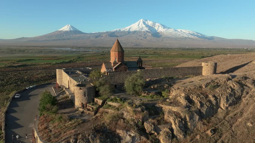 A drone flying over the historic monastery of Khor Virap towards Mount Ararat on a sunny day in the Ararat Plain in Pokr Vedi, Armenia