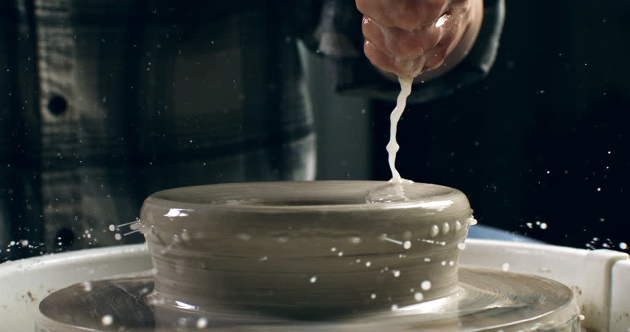 Super slow motion macro of skilled artisan potter shaping raw clay pot on  spinning wheel with artistry and dedication in his rustic workshop studio at 1000 fps.
