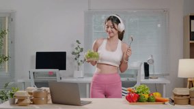Healthy woman preparing and eating organic fruit and vegetable salad in kitchen for healthy lifestyle and listen to music in headphone - Powered by Shutterstock - Get 15% off with code: PIKWIZARD15