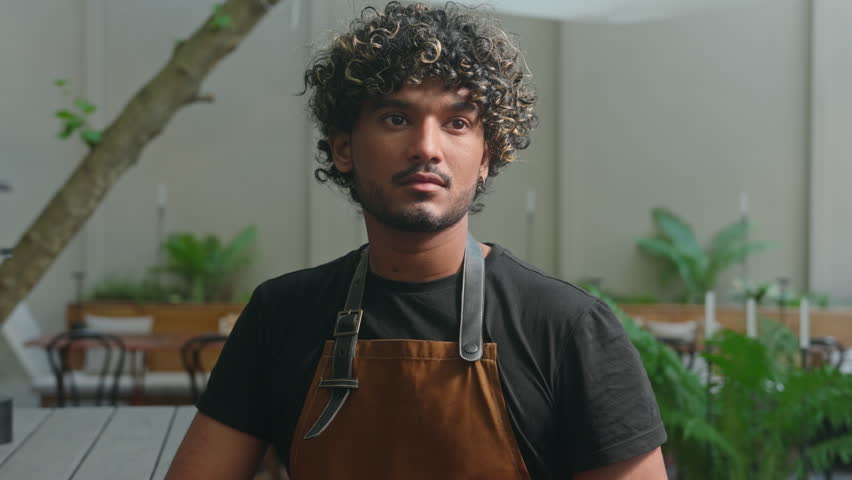 Happy joyful Latino American ethnic man male smiling cafe worker in apron guy waiter cleaner barista portrait small business owner employee looking at camera smile outside town. Employment street food