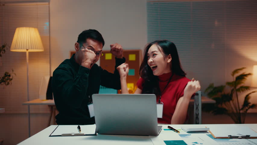 Business team celebrates a significant achievement while working late in the office. Excitement fills the air as partners express their joy over a successful project