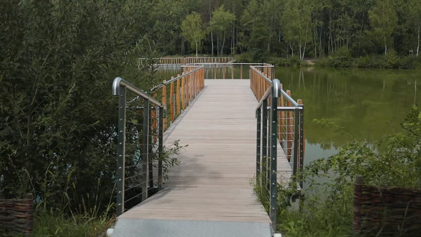 Wooden bridge over the autumn river lake. River bridge in autumn forest. High quality FullHD footage