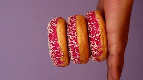 Stack of three Donuts in Male Hand. Woman putting Donut step by step on mans hand. Pink Doughnut with white sprinkles on pastel light purple background. Colorful Food. - Powered by Shutterstock - Get 15% off with code: PIKWIZARD15