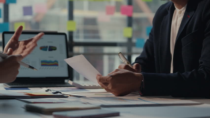 Business professionals engage in a meeting, discussing a contract while collaborating in an office environment