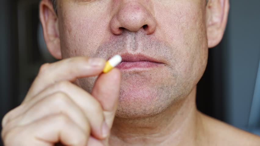 close-up. The man puts the pill in his mouth and washes it down with a glass of water. taking medications, vitamins and antibiotics as prescribed by a doctor.