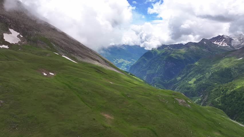 The großglockner high alpine road with green mountains and scattered clouds, aerial view