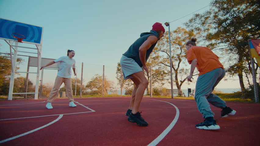 Sportive woman basketball player shoots ball into opponent hoop at playground. Experienced female athlete jumps receiving winning scoring for team