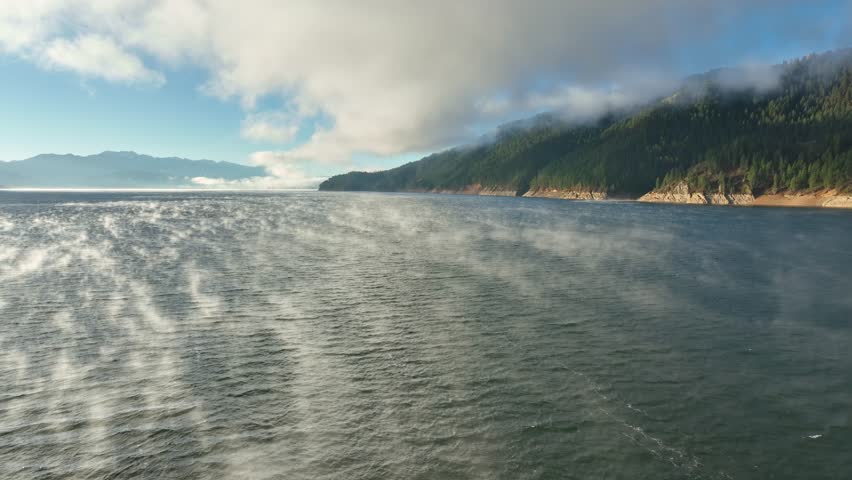Aerial of low clouds above the Palisades Reservoir on the Snake River in Idaho. Mist if coming off the water.