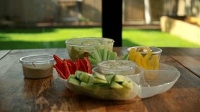 Fresh sliced vegetables and jar of hummus on table close up on veranda. - Powered by Shutterstock - Get 15% off with code: PIKWIZARD15
