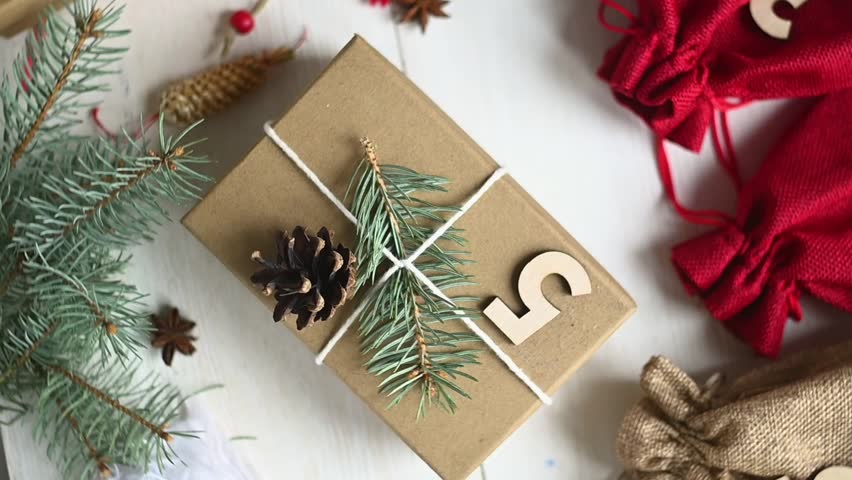 Merry Christmas. Christmas gifts and surprises on a white wooden table next to branches of a Christmas tree and shining lights. Advent calendar. Greeting card. top view. Layout. FullHD