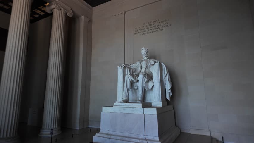Closeup view of the Lincoln Memorial statue in Washington DC. The marble sculpture depicts Abraham Lincoln seated in a chair, with his hands resting on the armrests.