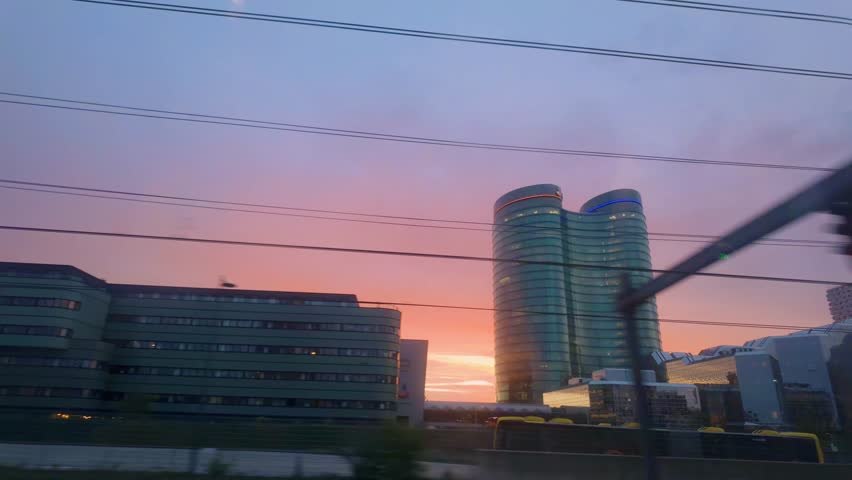 Train POV shot of Utrecht Central Station during sunset with clear view of Rabobank twin tower. Dreamy colorful sky effect, contrasting modern architecture and transport lines. Utrecht, Netherlands