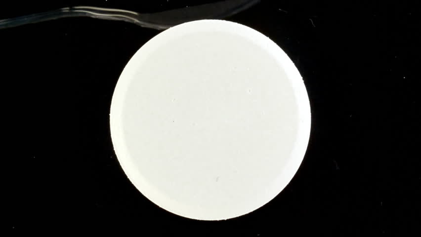 Close-up Effervescent tablet aspirin, vitamins on a black background. Macro shot of fine air bubbles in water in a petri dish. The medicine concept, health care, treatment. Slow motion.