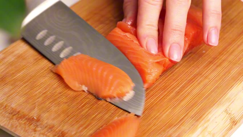 Cutting salmon on a wooden kitchen board 