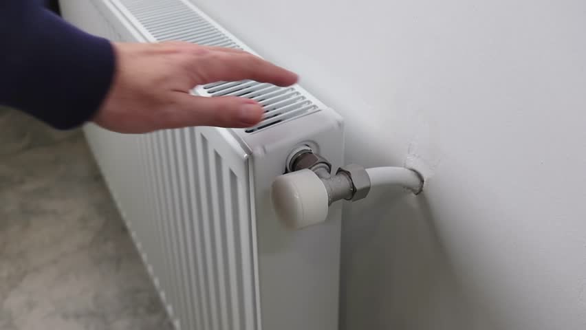 A man opens a valve on a radiator heating in an apartment or house. The beginning of the cold season.