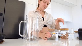 woman makes herbal tea in her kitchen. She adds leaves of mint, lemon balm, thyme, and rosemary to teapot . woman enjoys delicious and aromatic beverage. - Powered by Shutterstock - Get 15% off with code: PIKWIZARD15