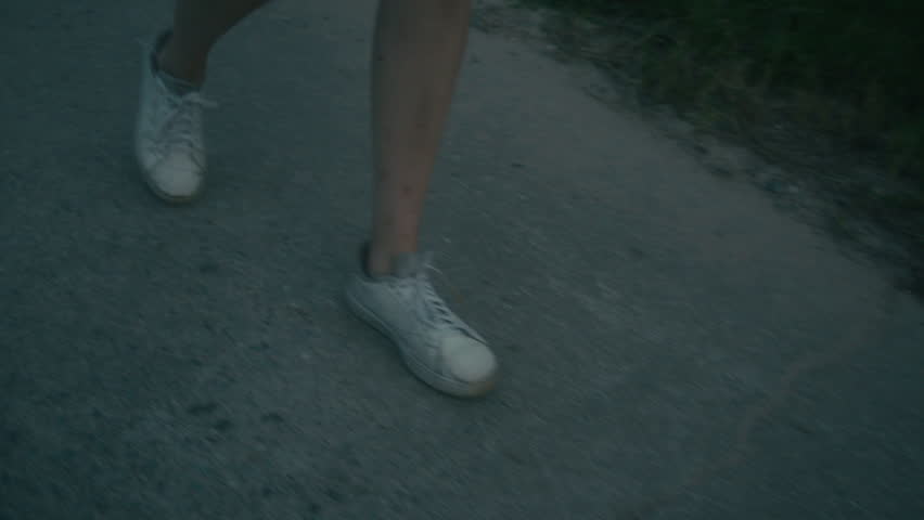 A young woman is walking down the road trying to catch a hitchhiker