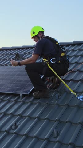 Engineer checking performance on a tablet while installing solar panels on a house. Vertical 9:16 video orientation