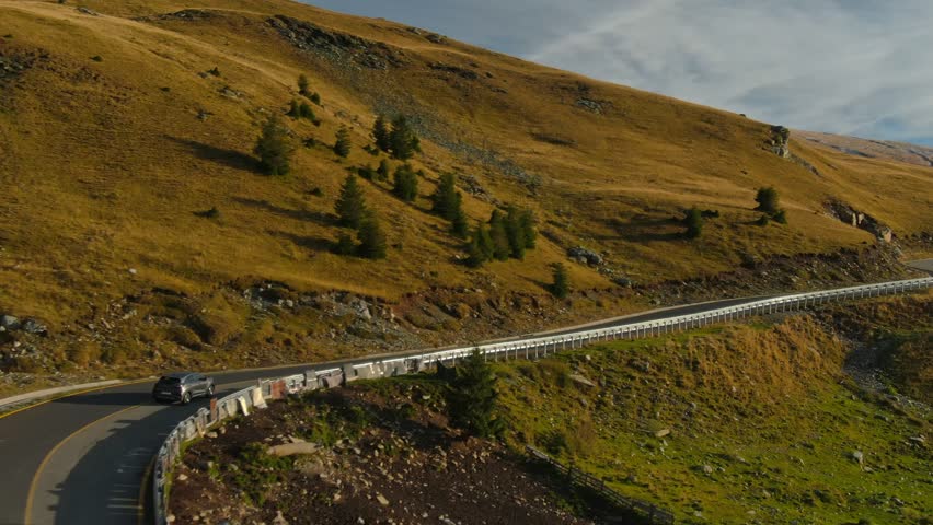 Establishing aerial rolling shot of Ford Puma hybrid vehicle driving on mountain road. Electric car driving fast on the road. Sustainable energy concept