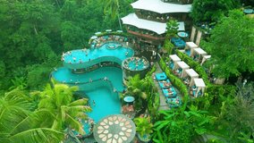 A vibrant pool area featuring multiple swimming pools, surrounded by lush greenery, offering relaxation and recreation for visitors in Tegalalang, Ubud, Bali. - Powered by Shutterstock - Get 15% off with code: PIKWIZARD15