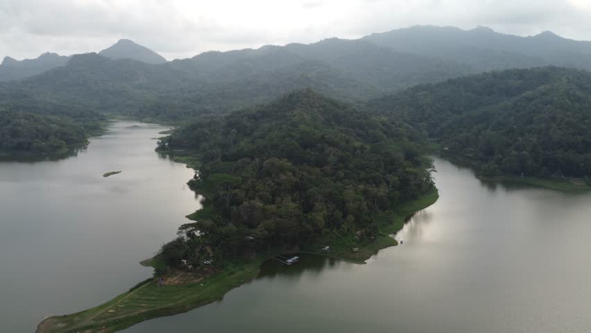 Aerial view of the island inside the reservoir and lake with the hills on the background