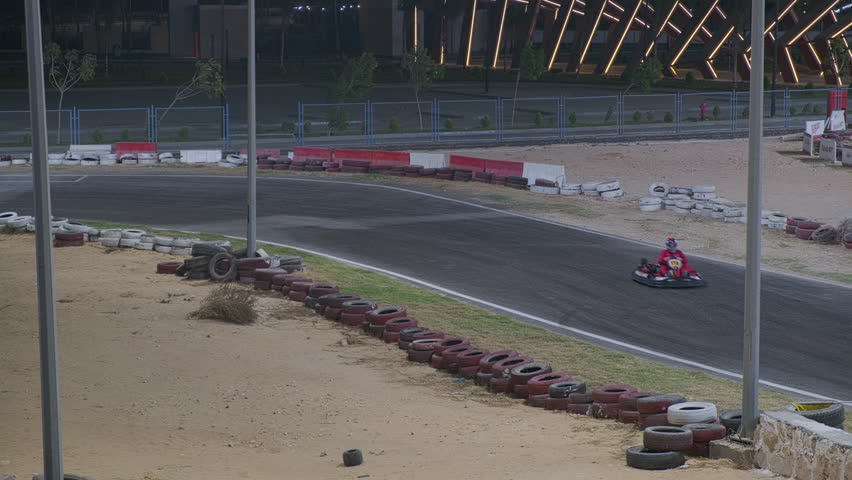 Unrecognizable people driving at go-cart racing track in the evening