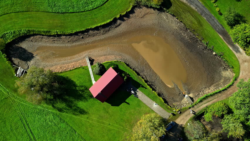 Time lapse shot of rural house beside a dried pond during summer afternoon. Drone view.