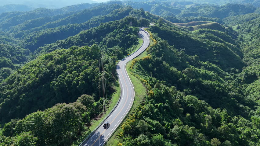 Aerial view of cars driving on a beautiful road, a famous road in Nan Province, Thailand, Road Number Three. Transportation Concept.