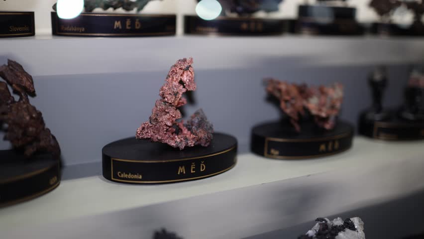 Close-up of copper mineral specimens, originating from locations like Caledonia. The intricate, naturally occurring formations showcase the earthy red tones of raw copper, highlighting its unique text