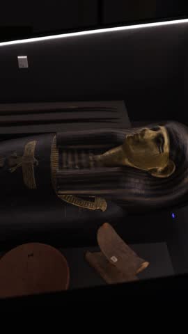 An ancient Egyptian mummy coffin adorned with gold and intricate symbols, displayed in a museum setting. The coffin’s detailed design reflects the craftsmanship and reverence for the afterlife in Egyp