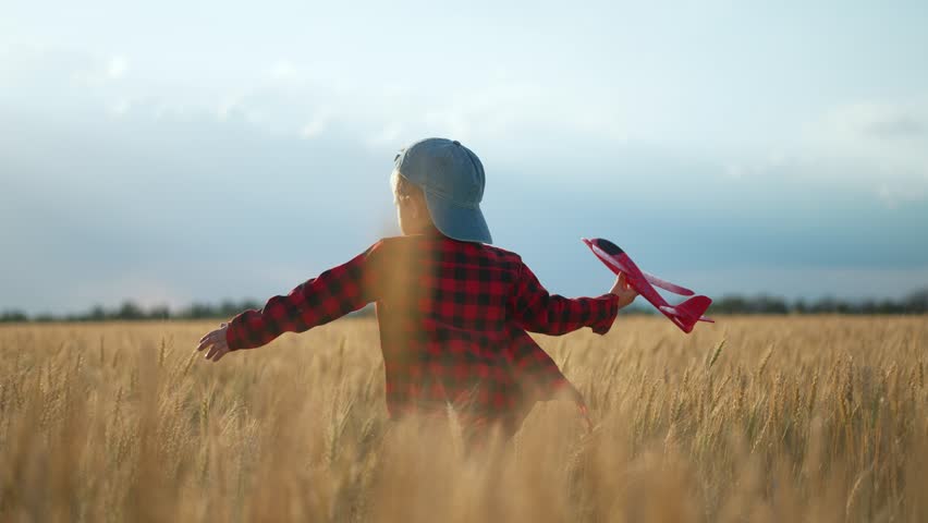 Happy Child with toy plane at sunset. Dream kid plays in field. Sunset sky inspiring child dream. Young aviator holding plane child imagination soaring. Happy child with plane at sunset. Dream big.