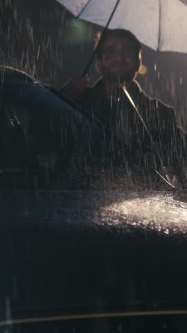 Vertical Screen: Handsome young man closes his umbrella and enters a car amidst a heavy rainstorm, with raindrops cascading down. Concept of shelter, transition, and resilience against harsh weather.