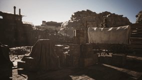 A rustic western settlement features weathered wagons and stacks of wooden crates as the sun sets, casting a warm glow on the dusty landscape. The rugged terrain adds to the historic atmosphere. - Powered by Shutterstock - Get 15% off with code: PIKWIZARD15