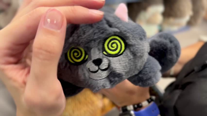 A quirky gray plush toy with spiral eyes, giving a playful and hypnotic look, perfect as a fun and unique gift or decorative item.