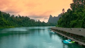 Water villas line the pristine lake, surrounded by lush greenery and majestic mountains, creating a picturesque escape in Cheow Lan, Thailand at sunset time. Aerial drone view. - Powered by Shutterstock - Get 15% off with code: PIKWIZARD15
