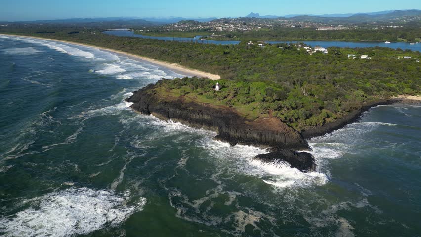Right to left rotating aerial looking at Fingal Head Lighthouse from over the ocean on a sunny day, Northern New South Wales, Australia.