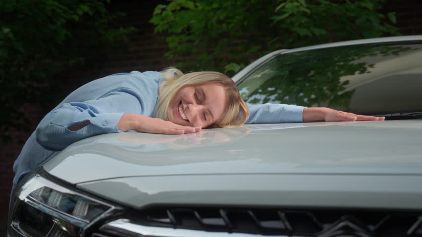 Smiling happy Caucasian woman lady touching hug automobile glad female driver girl lying hood businesswoman buying new transport in city car owner buyer celebrating purchase auto rent service vehicle