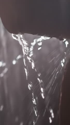 Water in shower flows from elbow of young woman. Lady washes in shower with water flows down body. Woman enjoys hundreds of drops flows down body
