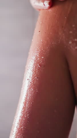 Woman peels skin with scrub in shower cabin closeup. Elegant lady cleans body skin with natural cosmetic product in bathroom. Enjoying skincare spa