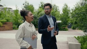 Multiracial business people walking in city multiethnic colleagues Caucasian businessman man male guy African woman businesswoman girl female talking walk conversation go to office hold laptop folder - Powered by Shutterstock - Get 15% off with code: PIKWIZARD15