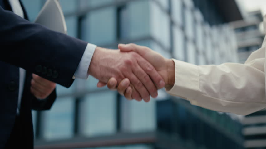 Close up unrecognizable multiracial business meeting in city colleagues Caucasian businessman man male guy African woman businesswoman girl female handshaking shake hands formal greeting hold folder