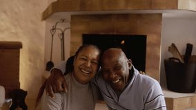Senior African couple by cozy fireplace having fun together - Elderly people inside wood cabin home - Powered by Shutterstock - Get 15% off with code: PIKWIZARD15