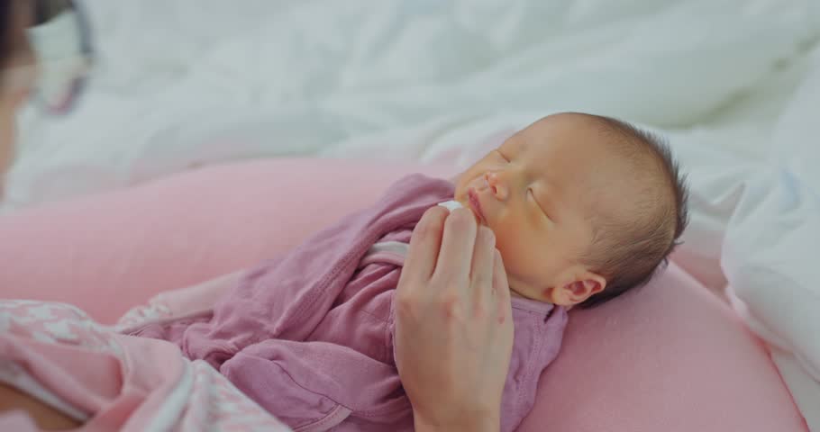 Mom help newborn baby to clean the mouth by using wet tissue