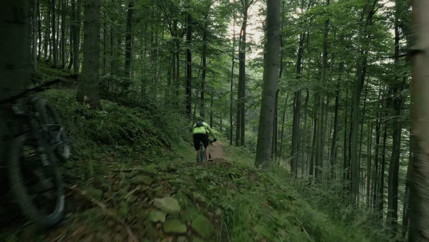 Aerial view of professional mountain biker going downhill on a forest trail.extreme sport mtb. Mountain biking action footage. Mtb riding a downhill bike along trail in the mountai.