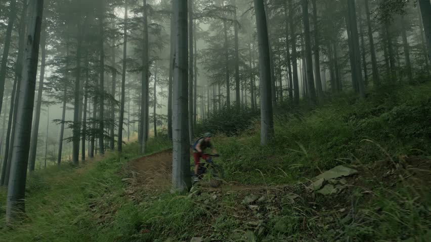 Aerial view of professional mountain biker going downhill on a forest trail.extreme sport mtb. Mountain biking action footage. Mtb riding a downhill bike along trail in the mountai.